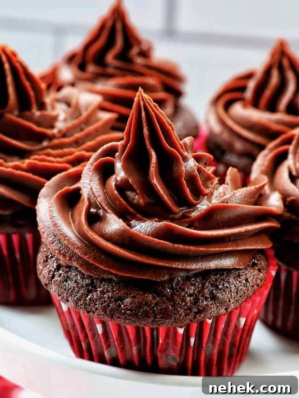 chocolate cupcakes with chocolate fudge frosting stacked on a cake pedestal.