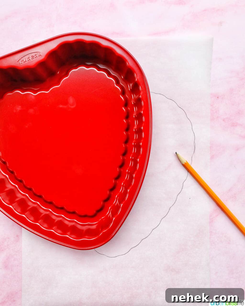 red heart-shaped baking pan over parchment paper and a pencil.