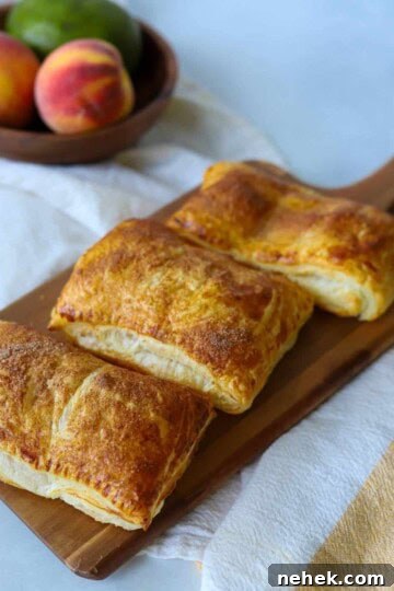Three peach mango pies on a wooden serving dish.