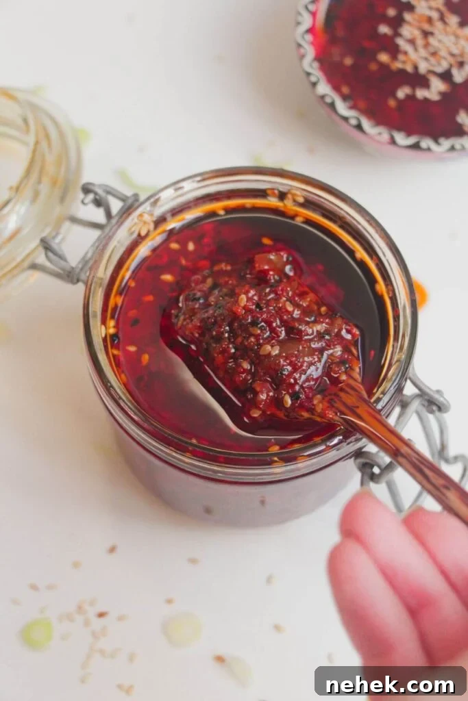 Hand holding a wooden spoon with chilli oil on it.