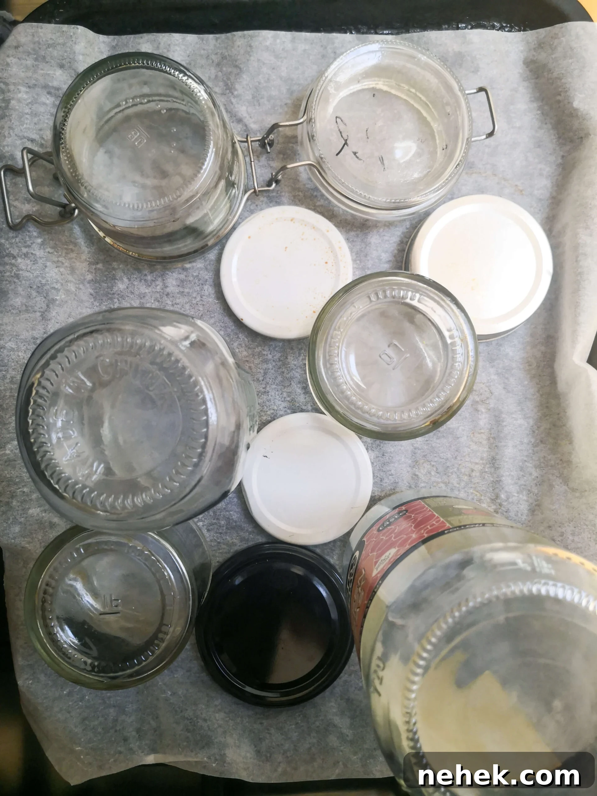 Glass jars standing upside down on a lined oven tray.
