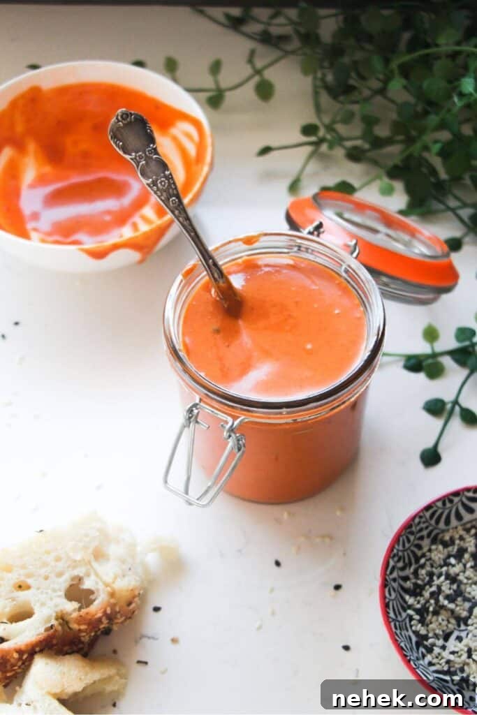 Gochujang mayo in a small glass jar with a bowl of more mayo in the background.