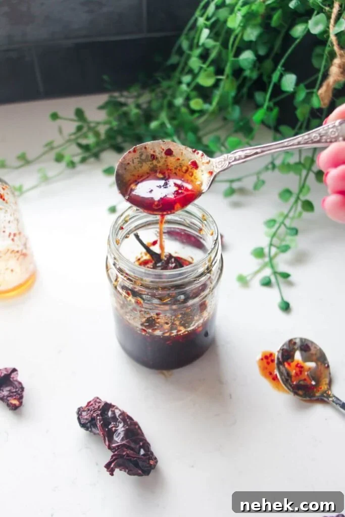 Hot honey drizzling from a silver spoon into a glass jar.
