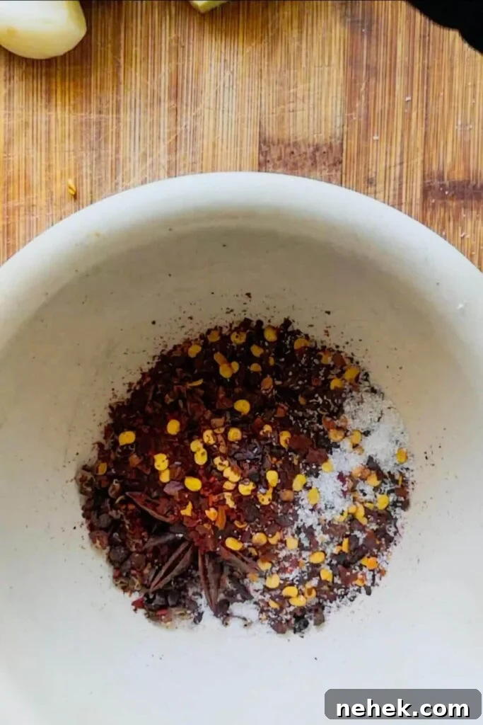 Chilli flakes, star anise, Szechuan peppercorns and salt in a white pestle and mortar.