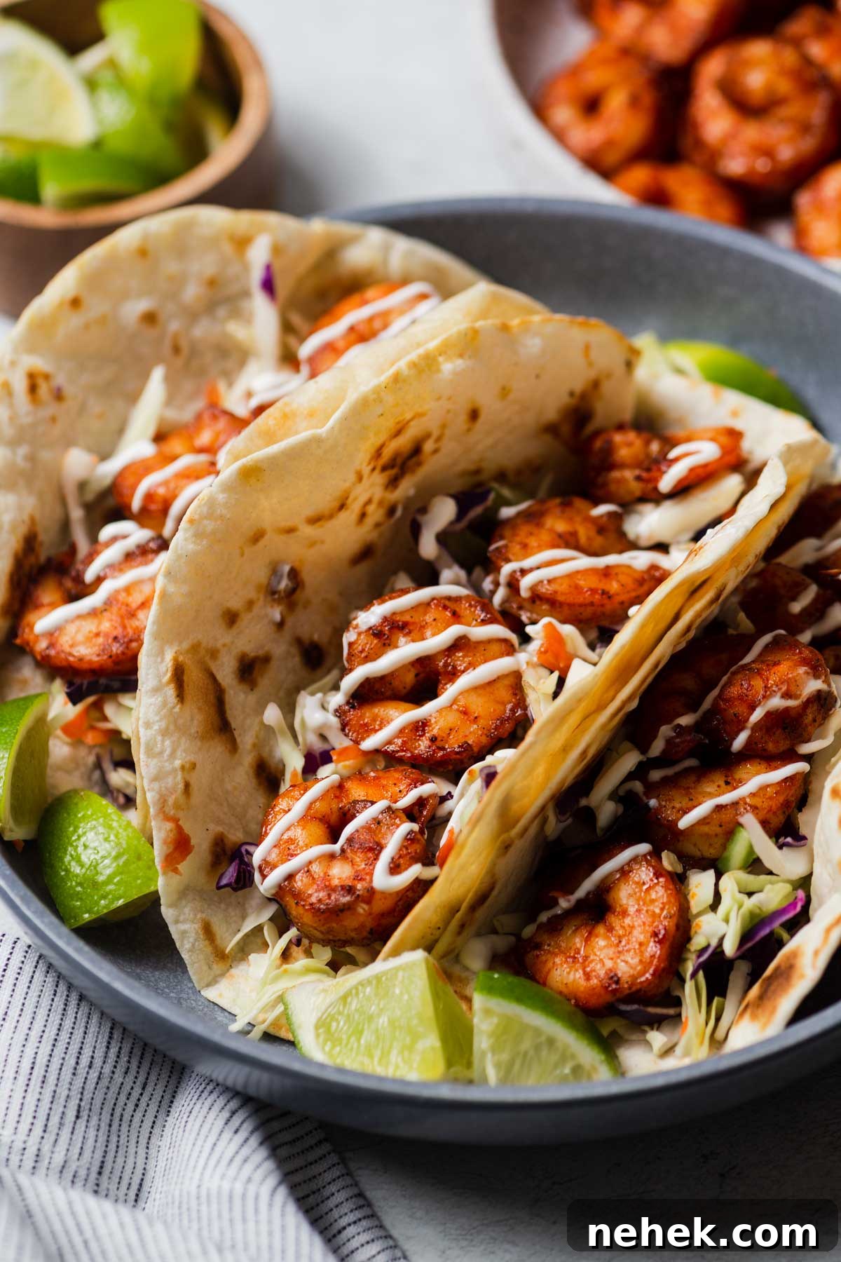 Crispy Air Fryer Shrimp Tacos with Lime Slaw 10 air fryer shrimp tacos drizzled with sour cream and lime wedges.