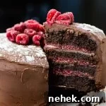 A layered chocolate raspberry cake with a piece being pulled away from it.