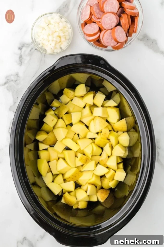 a prep image of a crockpot full of cubed potatoes with a bowl of sausage and chopped onions next to it.