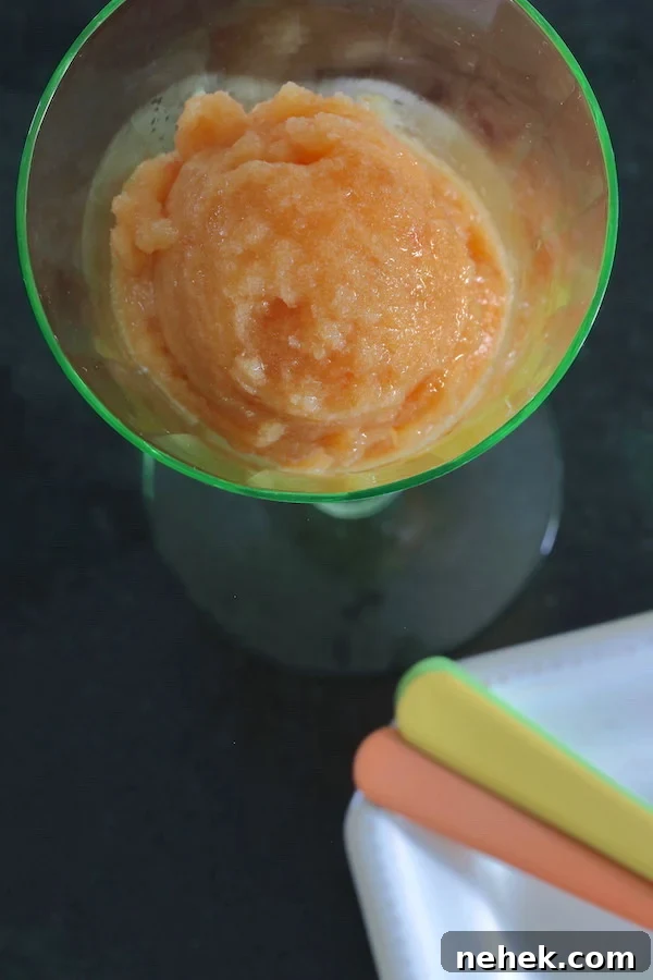 Sugar-Free Peach Sorbet Recipe — Light Summer Frozen Dessert 2 A scoop of peach sorbet in a pale green stemmed glass