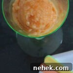 Sugar-Free Peach Sorbet Recipe — Light Summer Frozen Dessert 7 A scoop of peach sorbet in a pale green stemmed glass