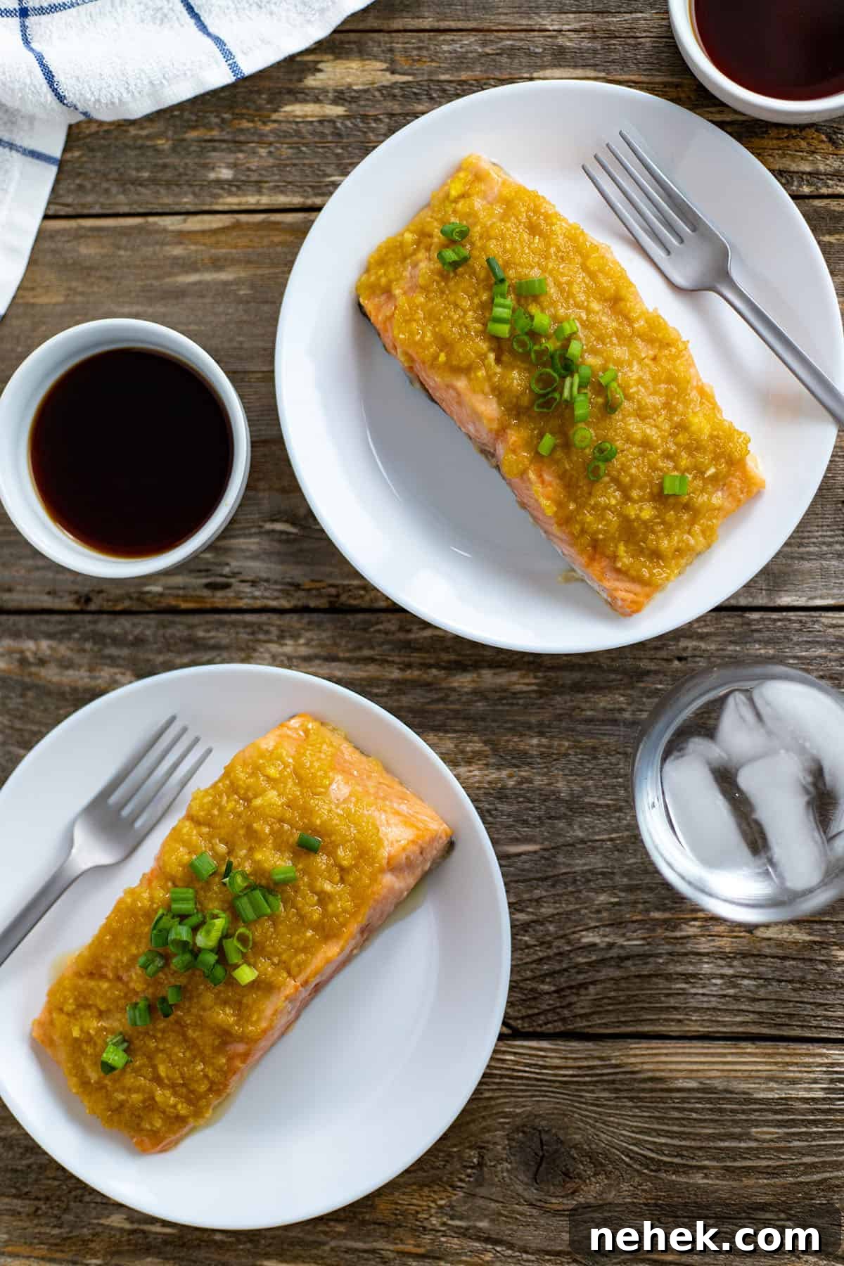 Two salmon fillets on white plates topped with miso ginger apple topping.