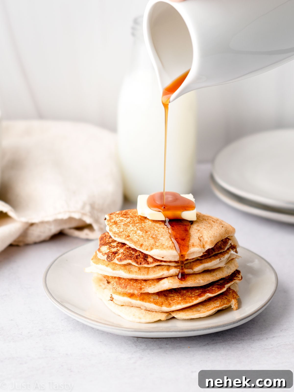 Stack of gluten free pancakes with syrup being poured on top.