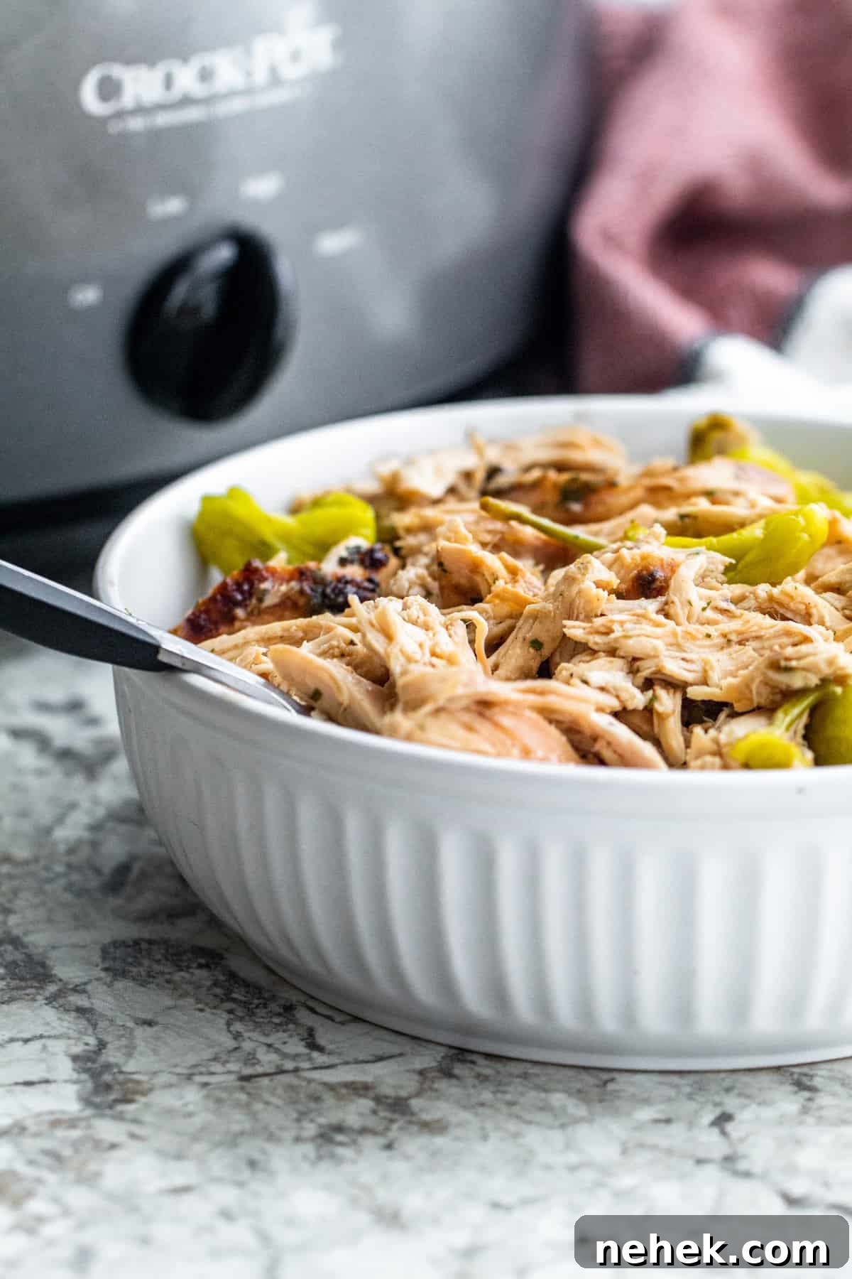 Slow-Cooker Mississippi Chicken with Creamy Sauce and Peppers 6 Mississippi shredded in large white bowl with fork in it.