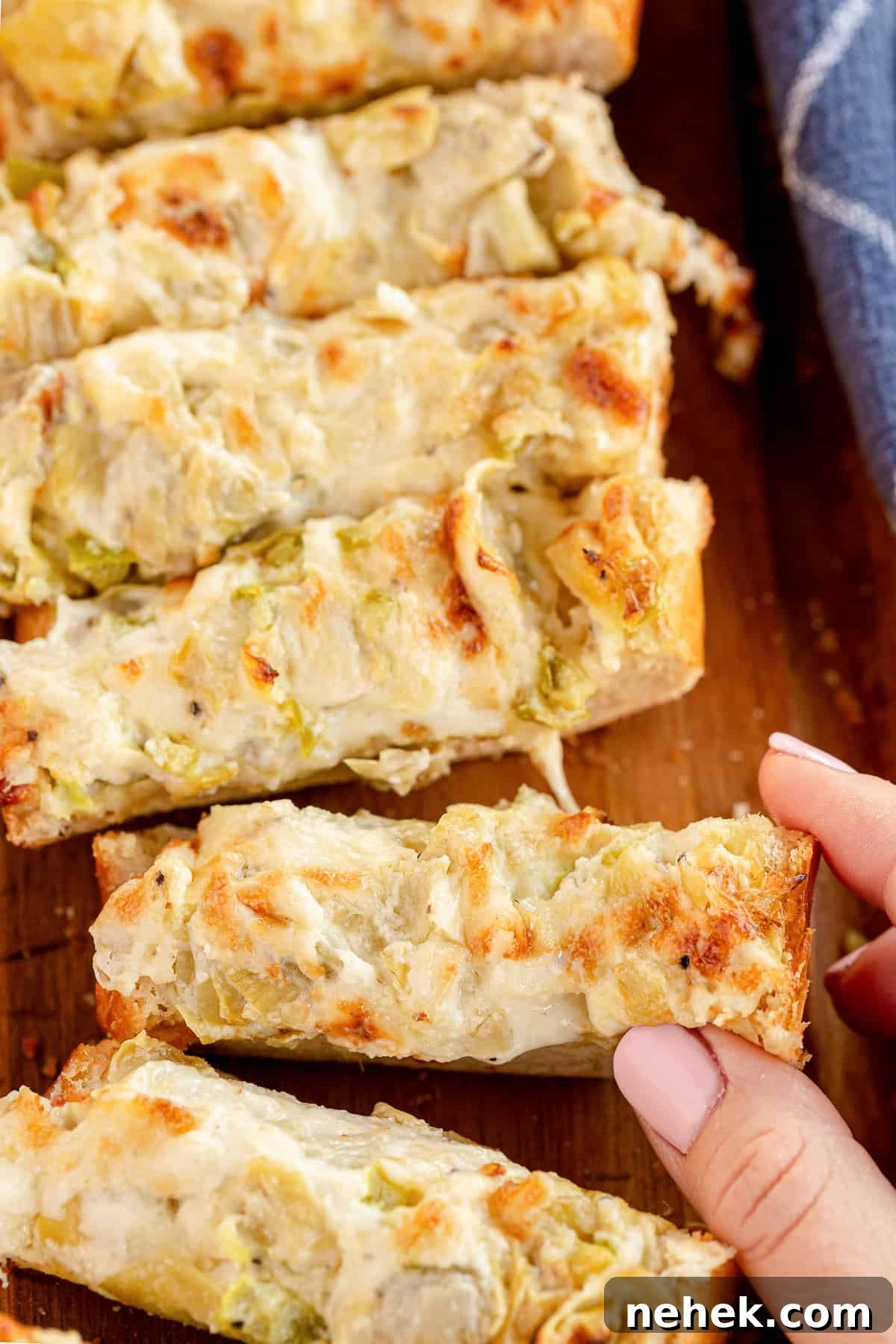 A hand taking a piece of Cheesy Artichoke Bread.