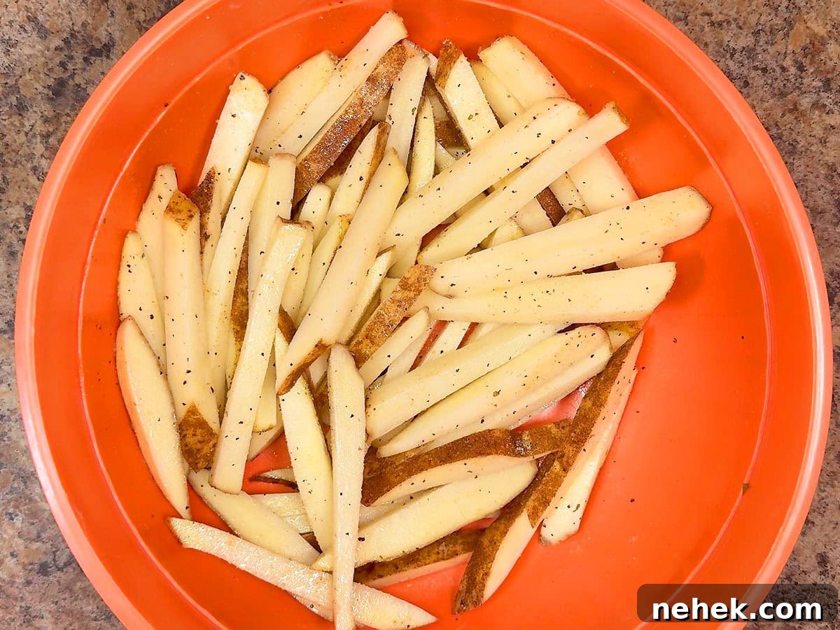 Crispy Oven-Baked French Fries Recipe for Perfect Crunch 6 Oiled and seasoned cut potatoes in a large bowl.