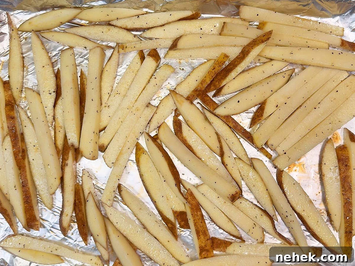 Crispy Oven-Baked French Fries Recipe for Perfect Crunch 7 Seasoned cut potatoes on a foil lined and greased baking sheet.
