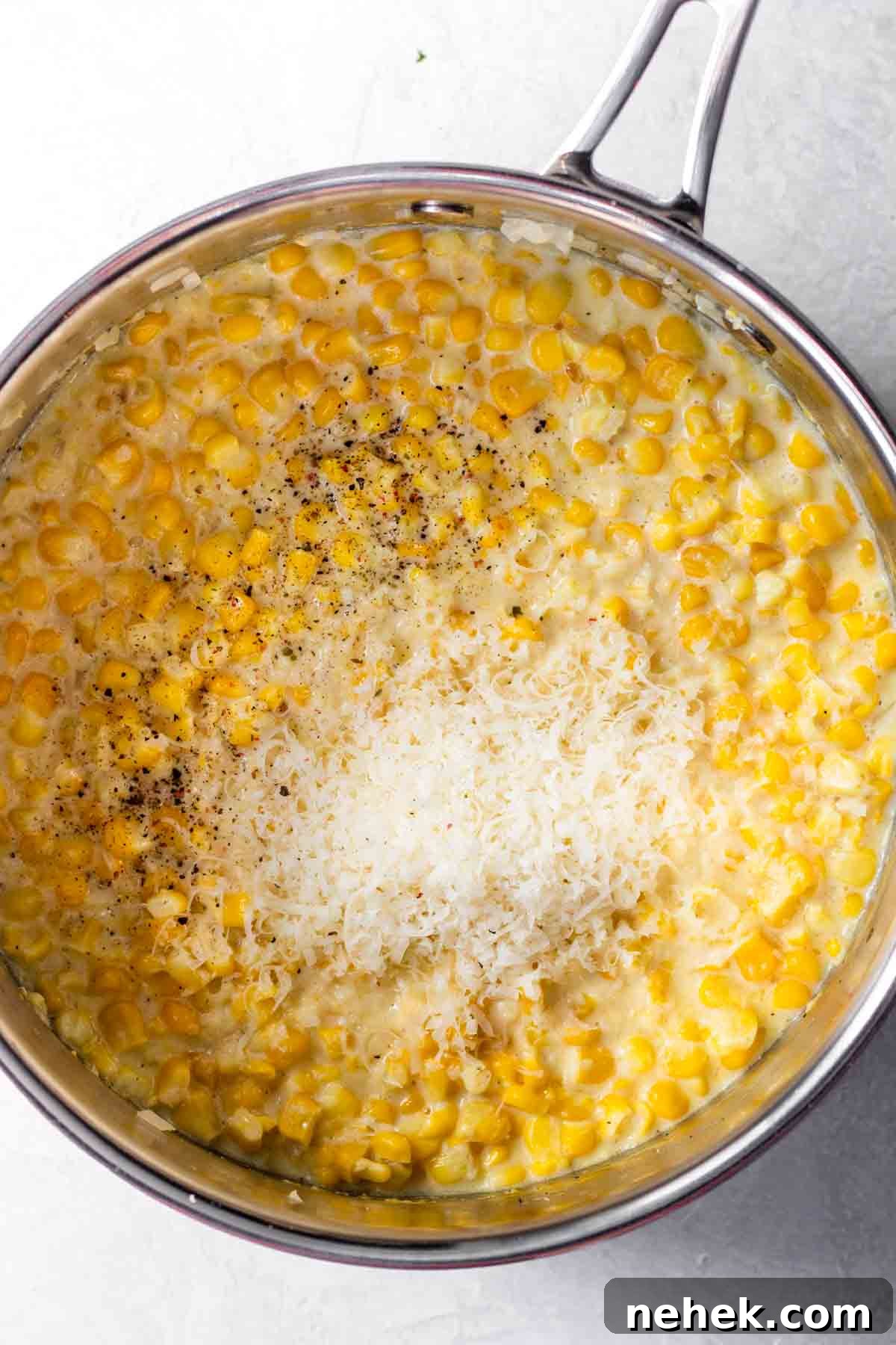 Pot filled with fresh corn, cream, seasonings and parmesan cheese to make homemade creamed corn.