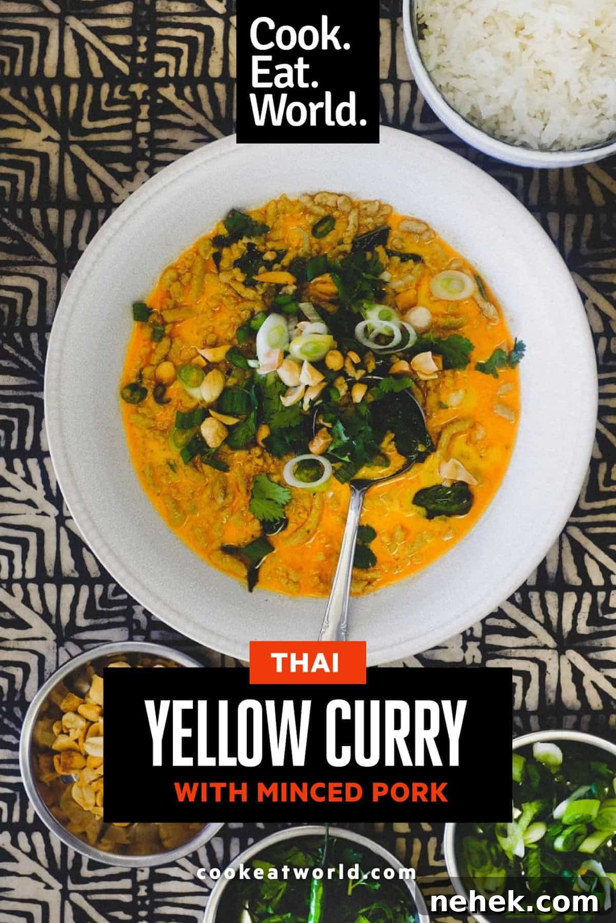 A bowl of Thai yellow curry with minced pork. Surrounding the bowl are smaller bowls of spring onions, cilantro, peanuts and jasmine rice.