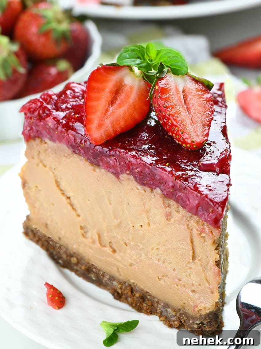 Piece of Strawberry Chocolate Cheesecake on a white plate garnished with two half strawberries.