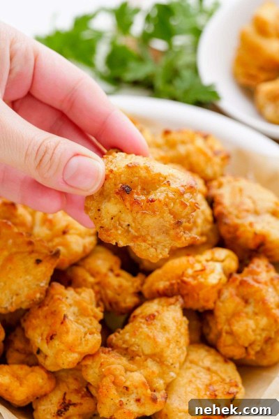 hand picking up popcorn chicken from air fryer