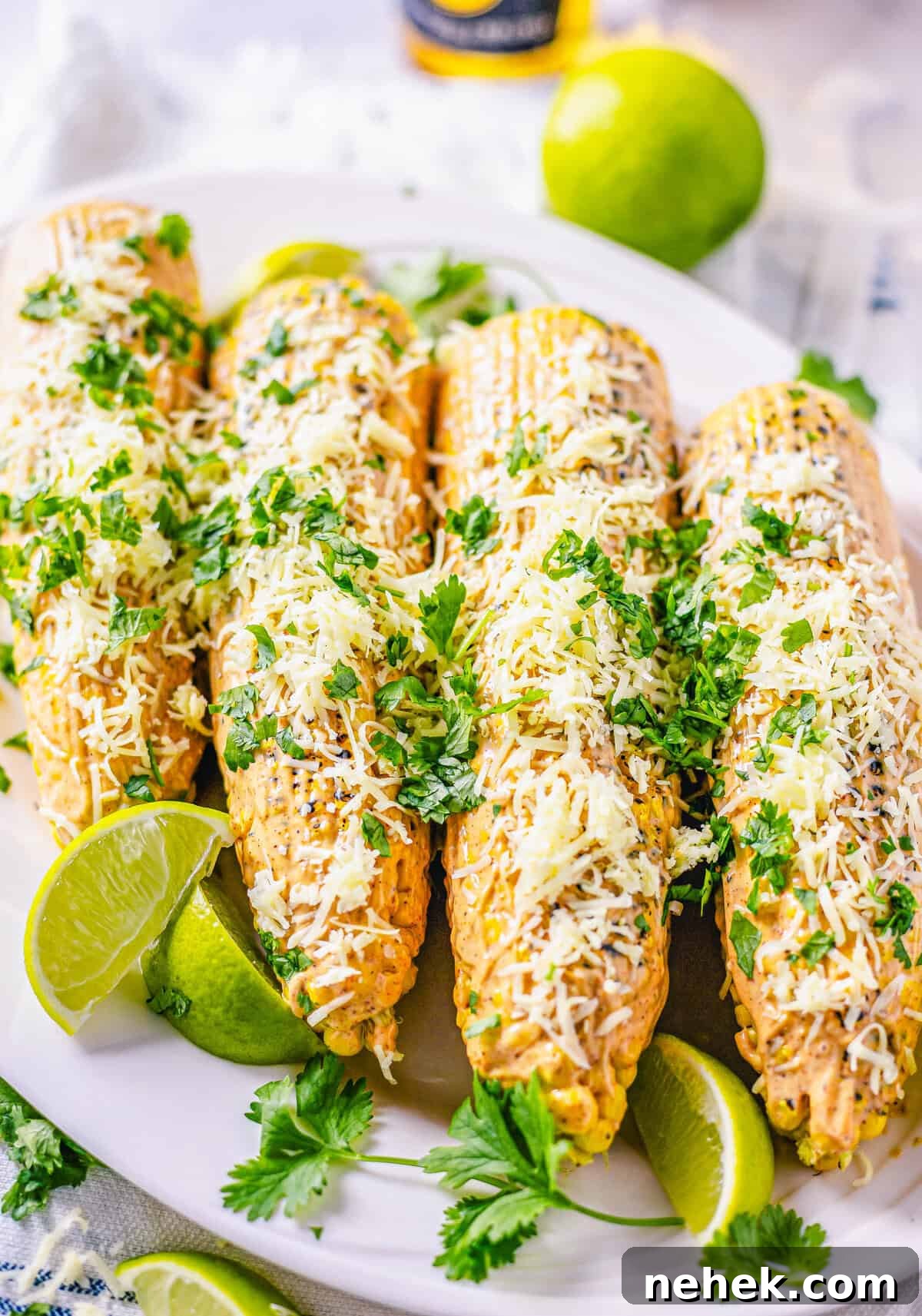 Smoky Chipotle Street Corn (Mexican Elote) Recipe 3 Side view of plated corn on platter garnished with limes and cilantro