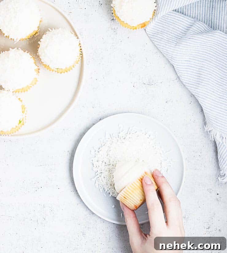 rolling frosted cupcake in coconut