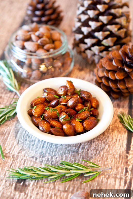 Rosemary Chipotle Roasted Almonds in white bowl with pinecones in background