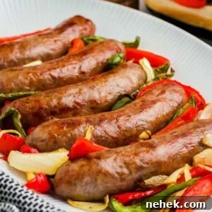 A white plate holds five air fryer brats garnished with sliced red and green bell peppers and onions. A black and white cloth is partially visible to the side.