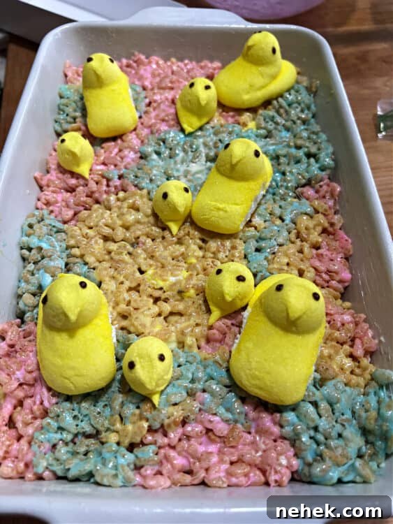 pan of peeps rice krispie treats decorated with whole peeps and some extra heads of peeps.