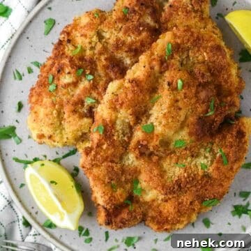 Chicken schnitzel on plate with lemon.