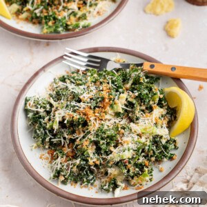 Two plates with kale caesar dressing for serving. A lemon wedge sits on the side of the plate for garnish.