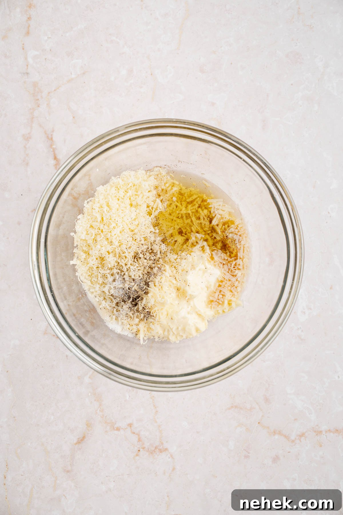 All of the ingredients for the Caesar dressing in a large glass bowl on a countertop.