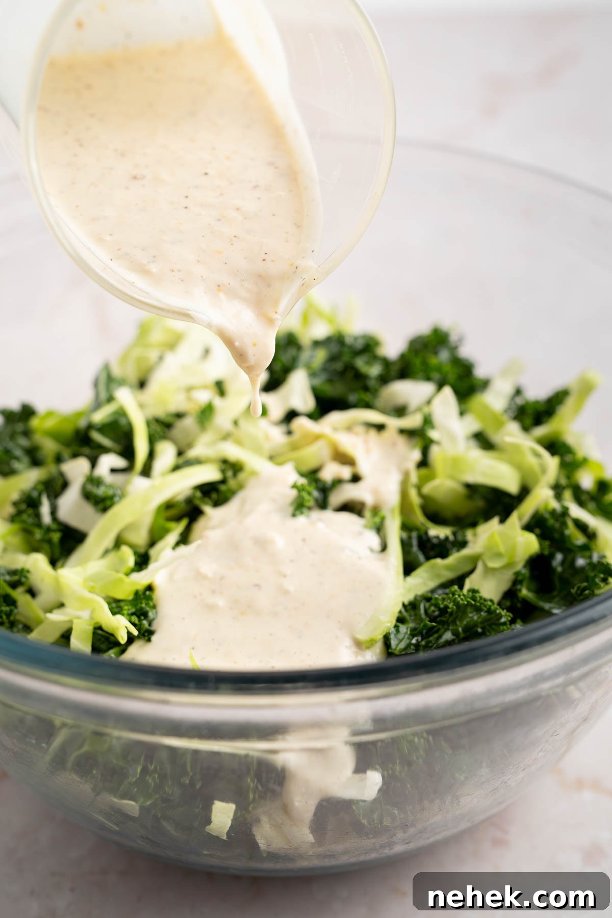 Pouring the dressing over the mixed kale and cabbage.