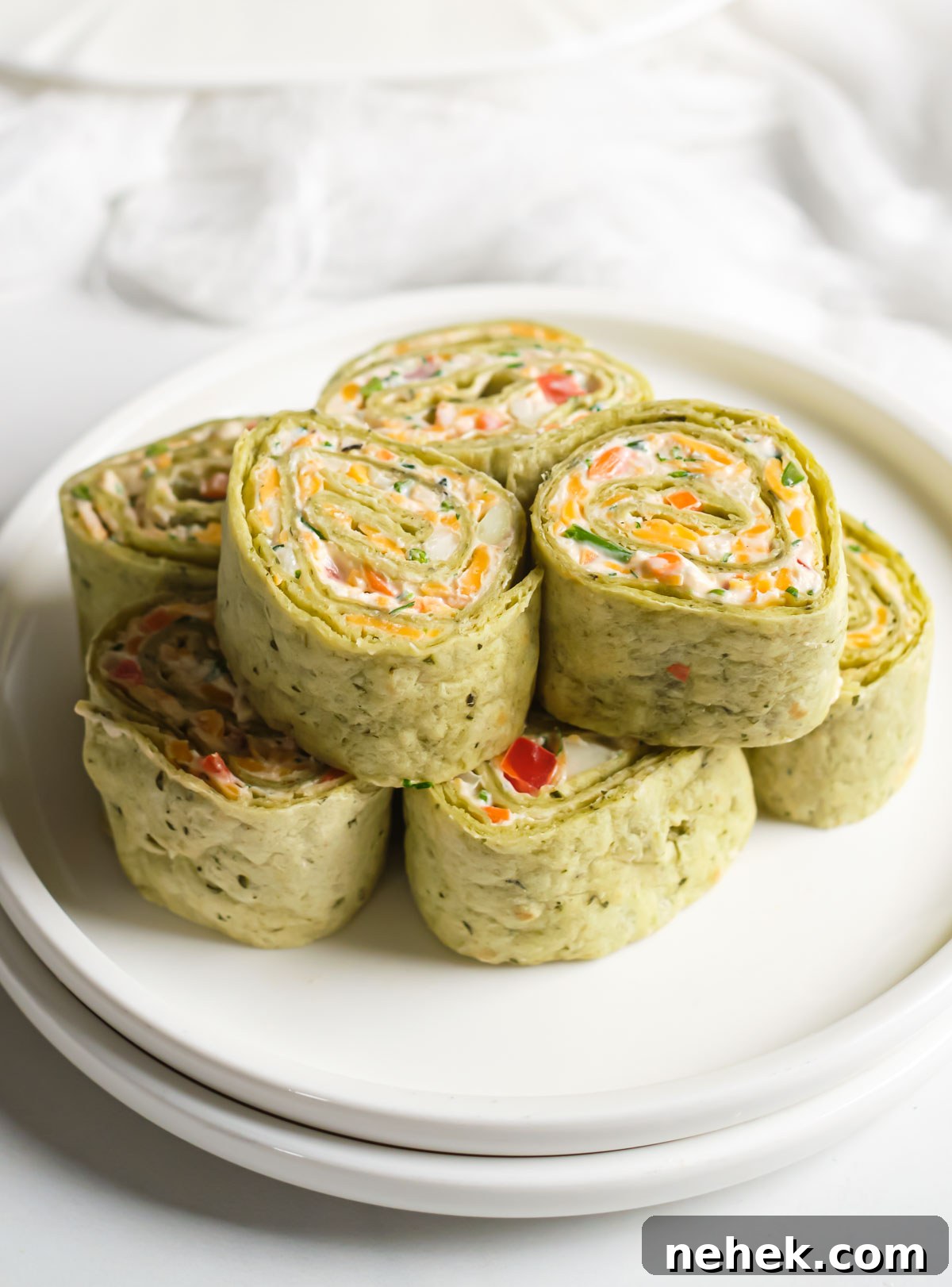 Crunchy Veggie Pinwheels with Cream Cheese and Herbs 2 one portion of pinwheels served on a white dinner plate