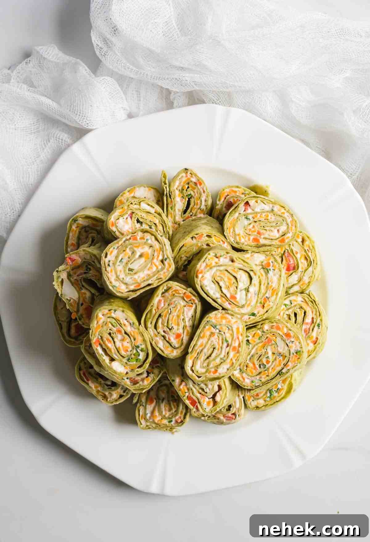 Crunchy Veggie Pinwheels with Cream Cheese and Herbs 11 a plate filled with sliced veggie pinwheel pieces
