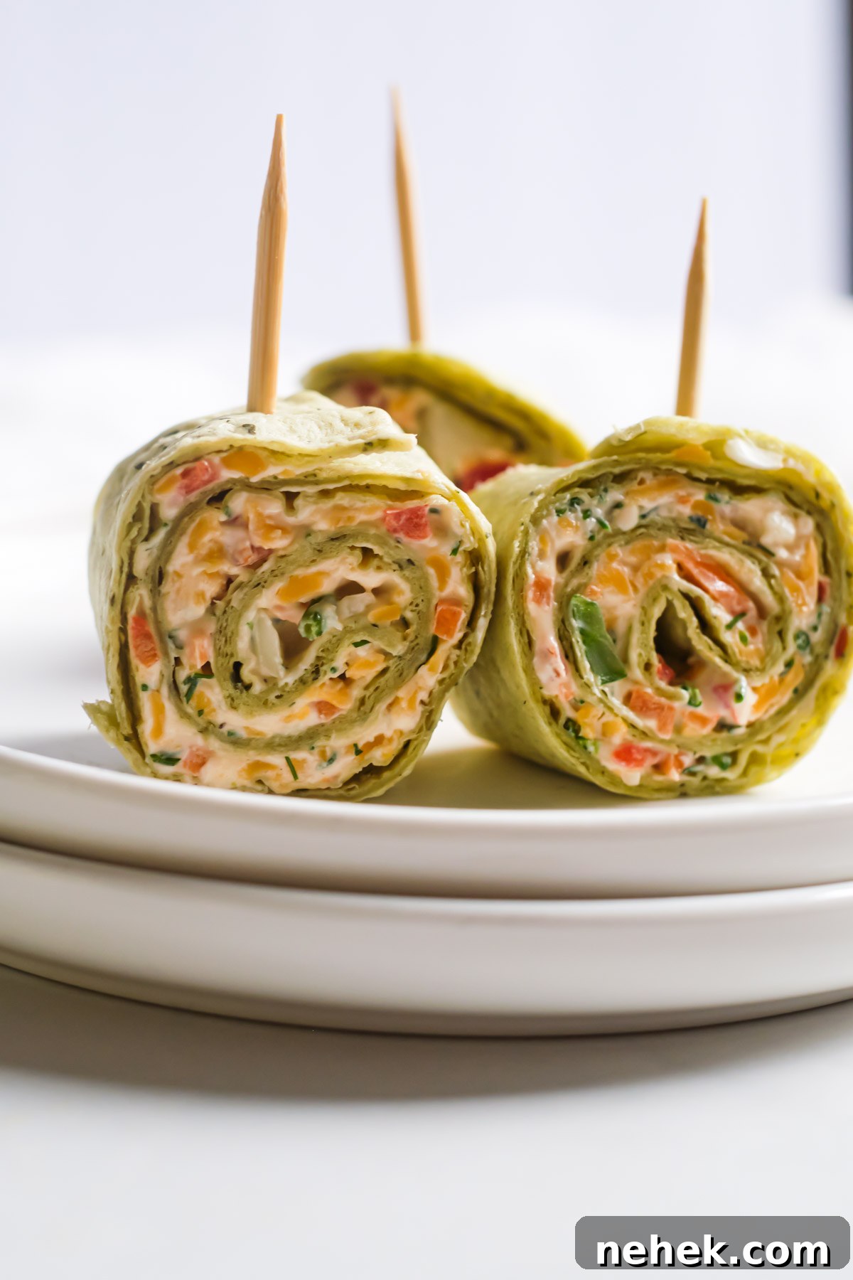 Crunchy Veggie Pinwheels with Cream Cheese and Herbs 12 three pinwheels with toothpicks inside on a plate