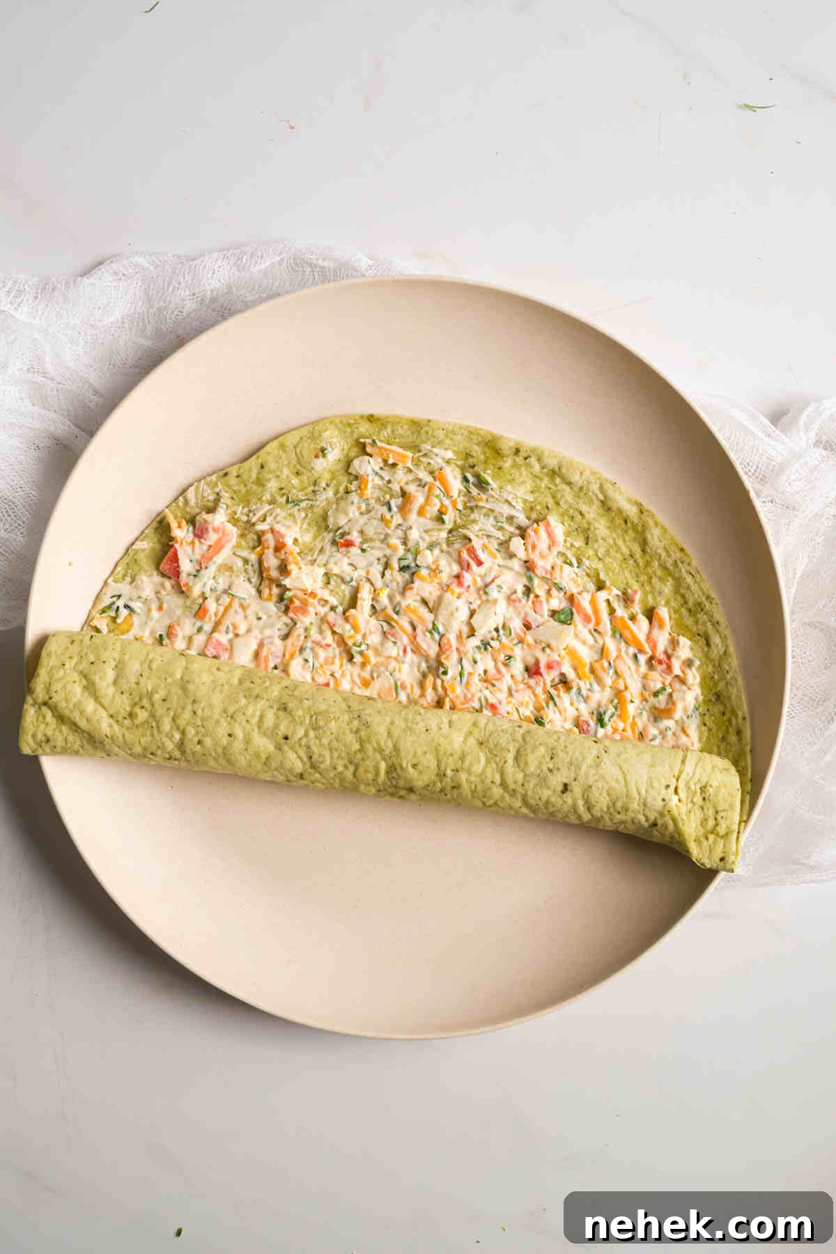 Crunchy Veggie Pinwheels with Cream Cheese and Herbs 8 the beginning of rolling up a filled tortilla