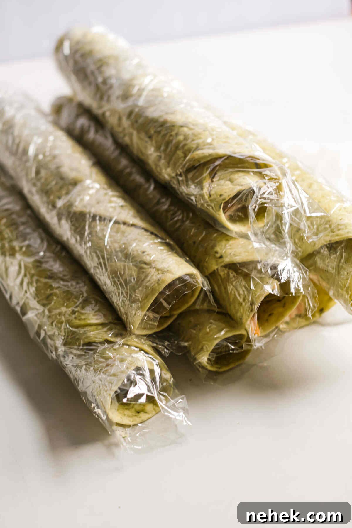 Crunchy Veggie Pinwheels with Cream Cheese and Herbs 10 the pinwheel roll ups wrapped in plastic wrap and ready to be chilled