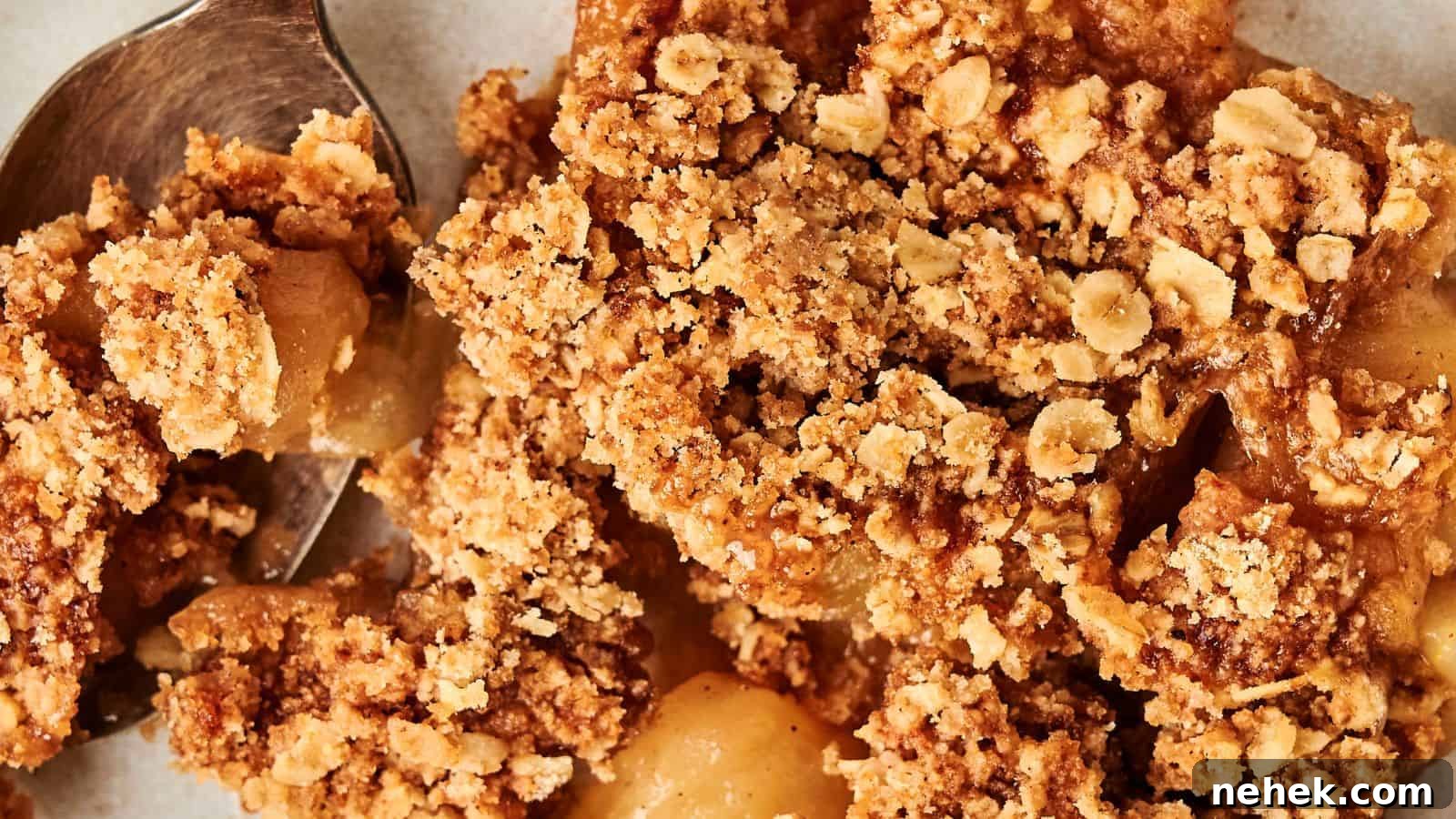 15 Delicious Easter Recipes to Make Your Celebration Shine 8 Close-up of apple crumble with oats and brown sugar topping. A spoon is partially visible on the left.