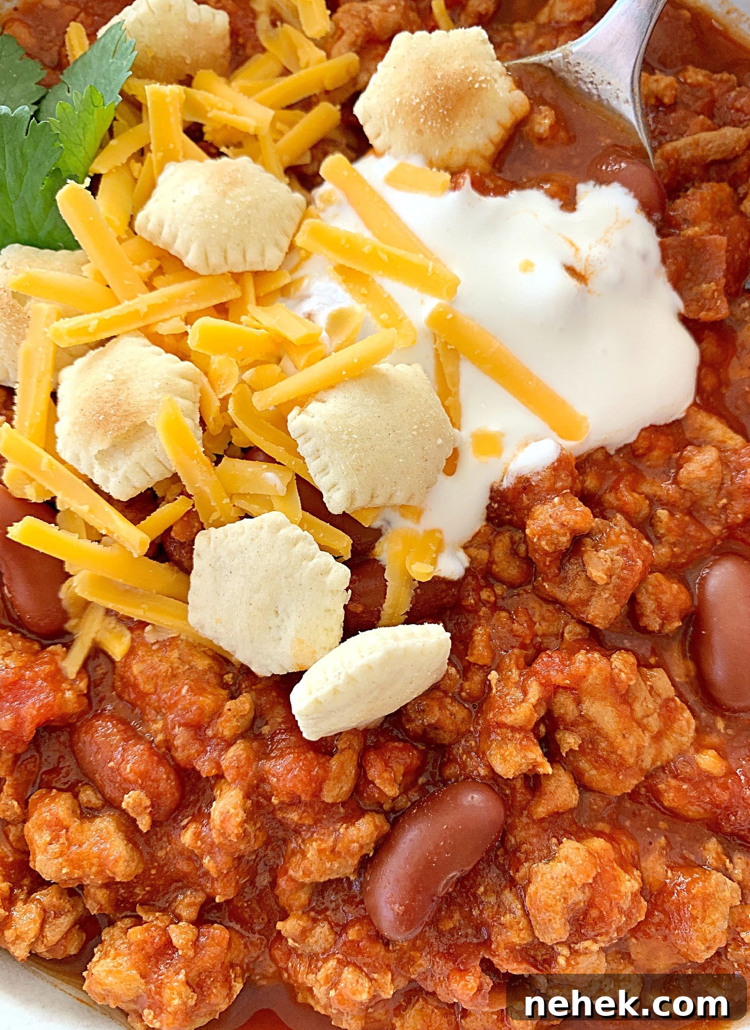 Slow-Cooker Turkey Chili Recipe: Hearty, Flavorful Meal 5 close up view of crockpot turkey chili topped with sour cream, oyster crackers and shredded cheese