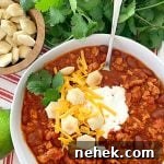 overhead view of turkey chili topped with sour cream, oyster crackers and shredded cheese