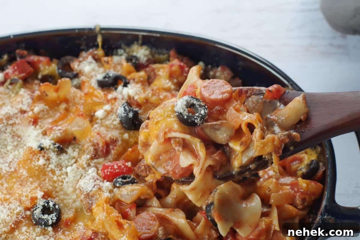 Low-Carb Pizza Casserole with Veggies and Mozzarella 11 spoonful of pizza casserole being held up on a dark wooden spoon over casserole dish