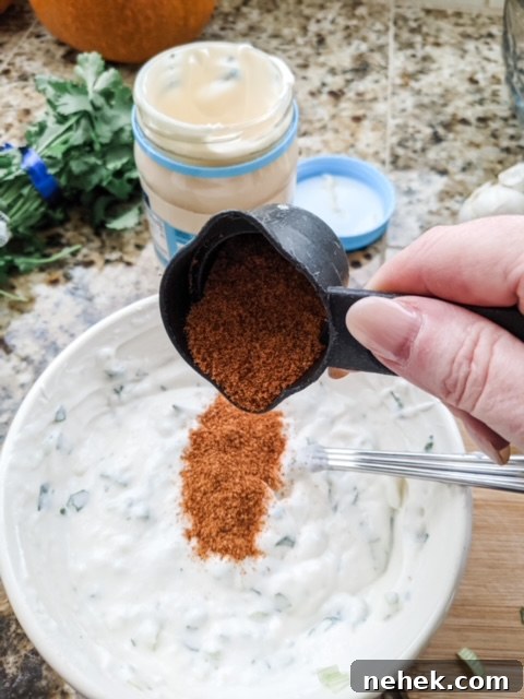 Marie dropping some of the taco seasoning into the Lighter Southwestern Buttermilk Ranch