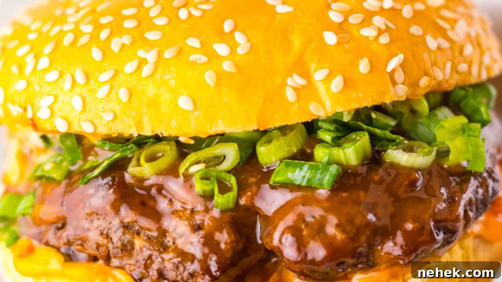 Close-up of a hamburger with a sesame seed bun, beef patty, green onions, and rich brown sauce.