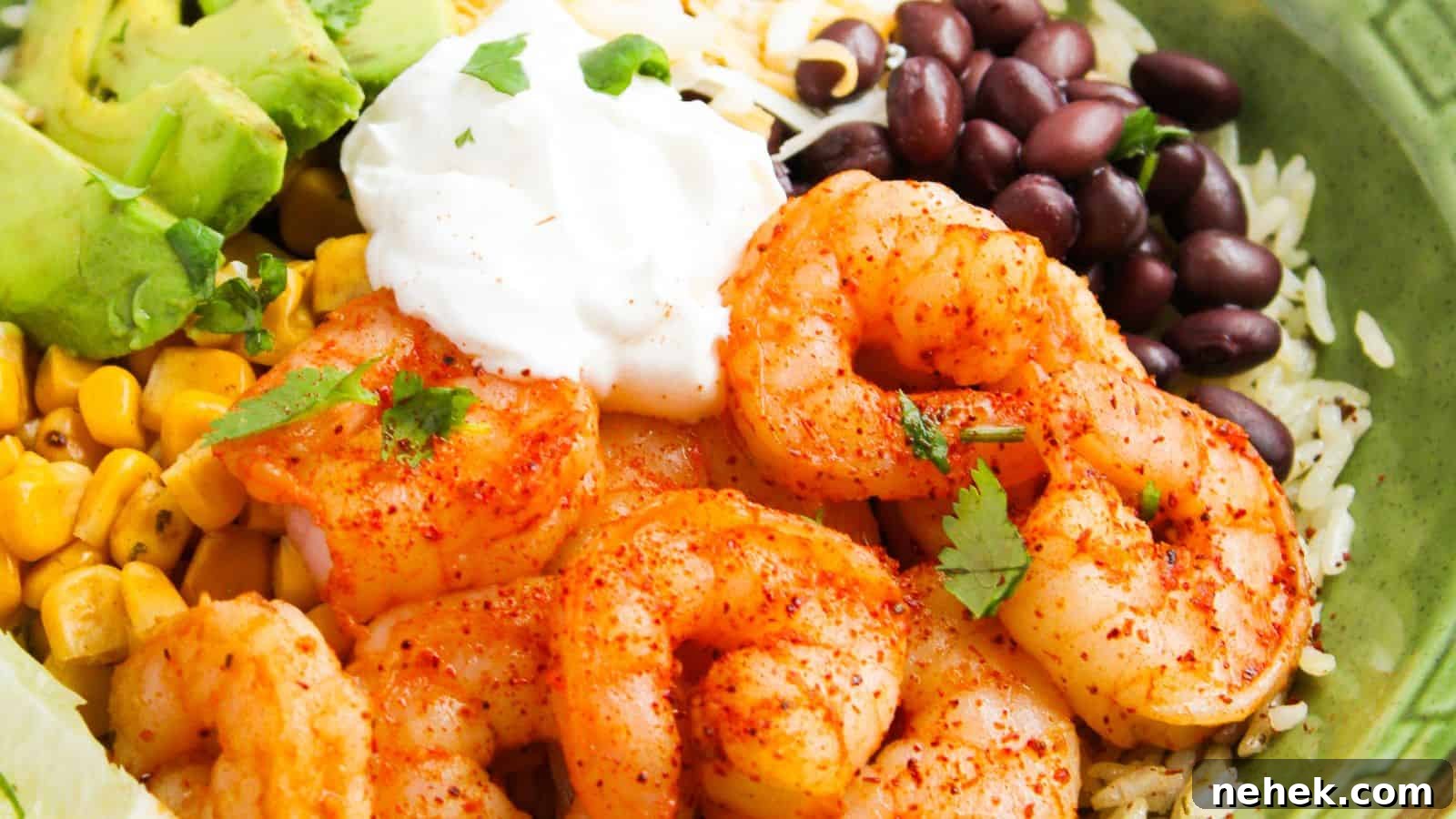 A bowl of seasoned shrimp, avocado, corn, black beans, rice, and a dollop of sour cream, garnished with cilantro.