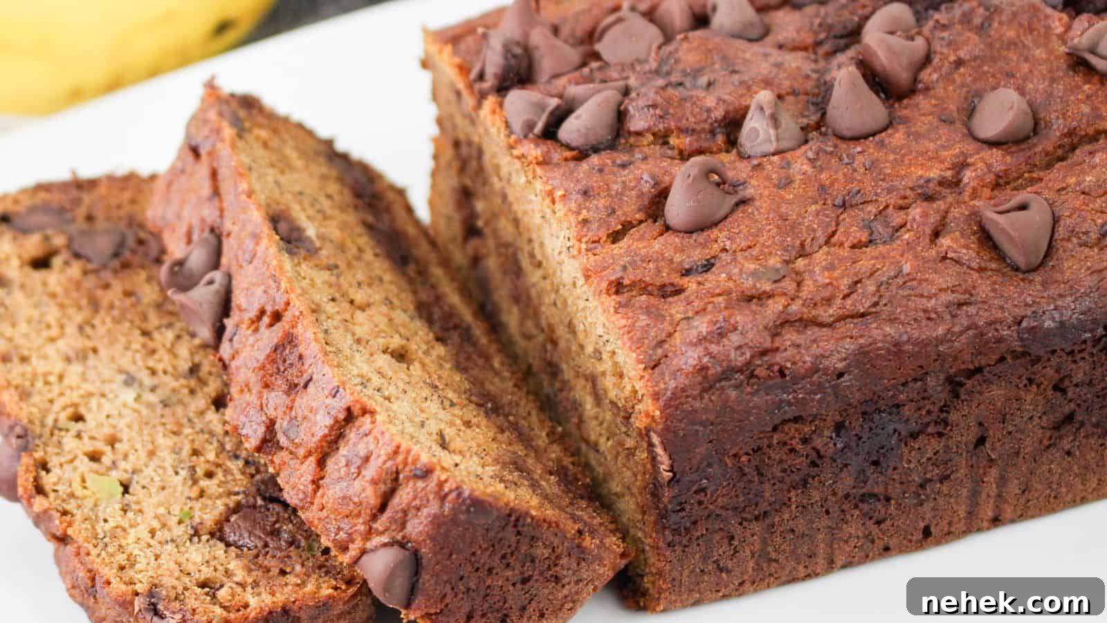 Sliced loaf of chocolate chip banana avocado bread on a white surface. The bread has a golden-brown crust with chocolate chips on top and visible throughout the slices.