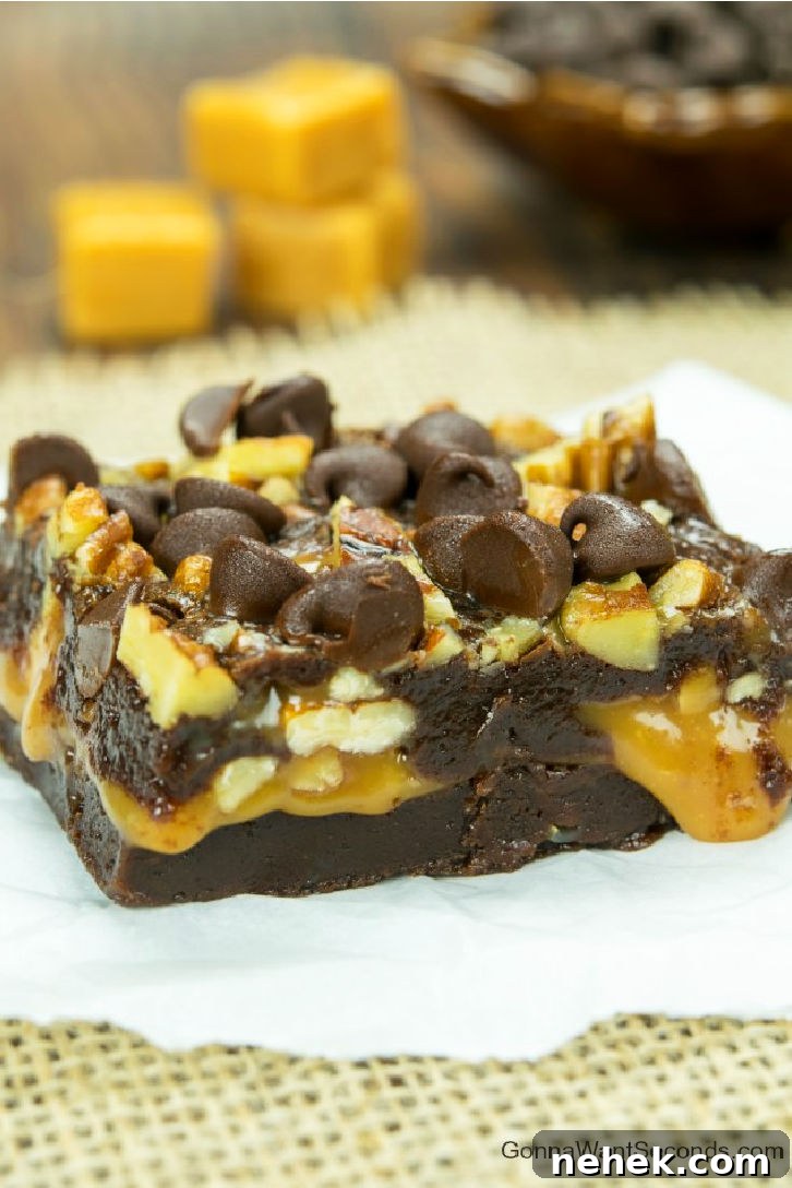 Caramel brownies are your tickets to brownie bliss – fudgy brownies wrapped around a thick, caramel layer, with crisp pecans and chocolate chips. a slice of Caramel stuffed brownies with chocolate chips and pecans on top