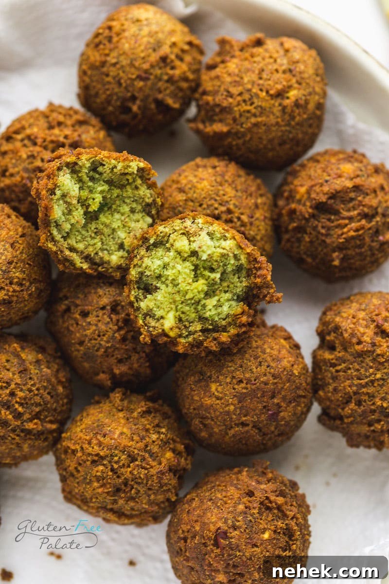 Crispy gluten-free falafel on a white plate one is open to show the soft, tender texture inside.