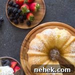 Kentucky Butter Cake on wooden cake stand with whipped cream and berries on a grey background.