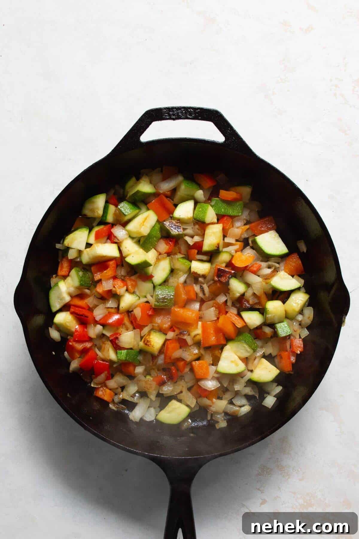 Sautéing onion, bell pepper, and zucchini in a cast iron skillet for shakshuka