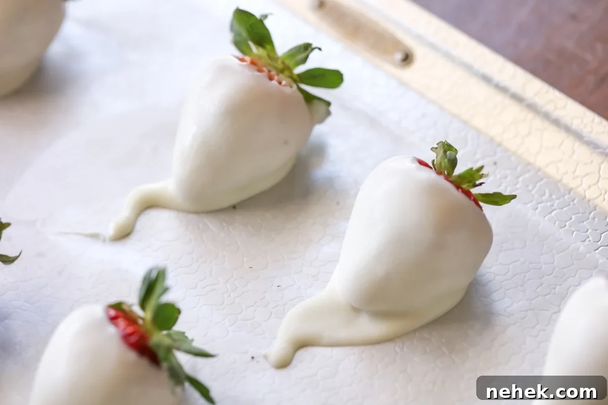 Juicy and sweet strawberry ghosts are spooky and delicious!! Here is a simple and quick tutorial on how to make these Boo-tiful treats. white candy coated strawberries on wax paper